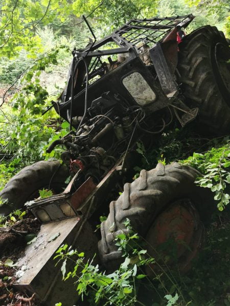 FOTO Un tractor s-a răsturnat ieri în munți, lângă Zărnești. Tractoristul a fost scos de salvamontiști dintre fiarele contorsionate ale utilajului agricol
